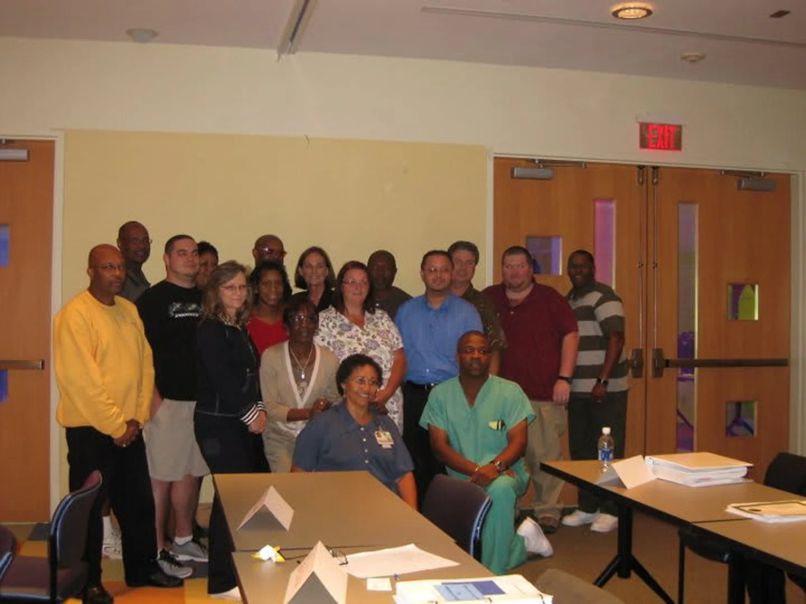 Photo of a man in a lab coat and PPE holding a Petri dish with a white version of the Sanofi logo superimposed in the middle foreground
